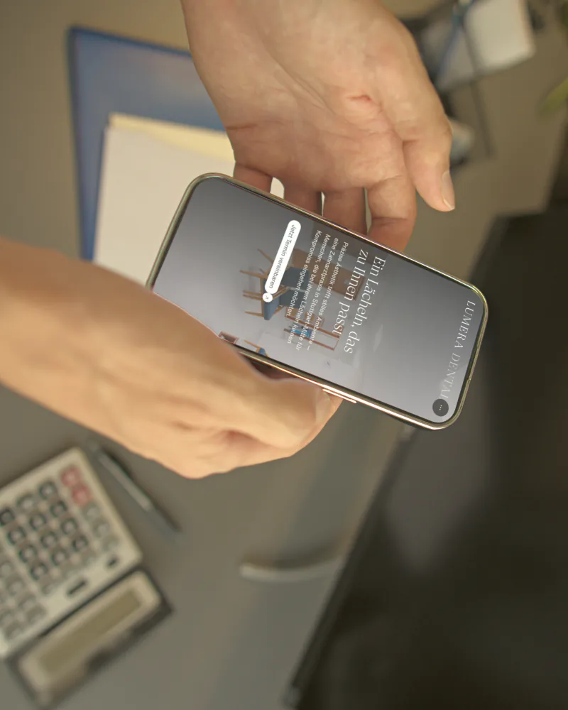 Hände halten ein Smartphone mit der mobilen Website von Lumera Dental
